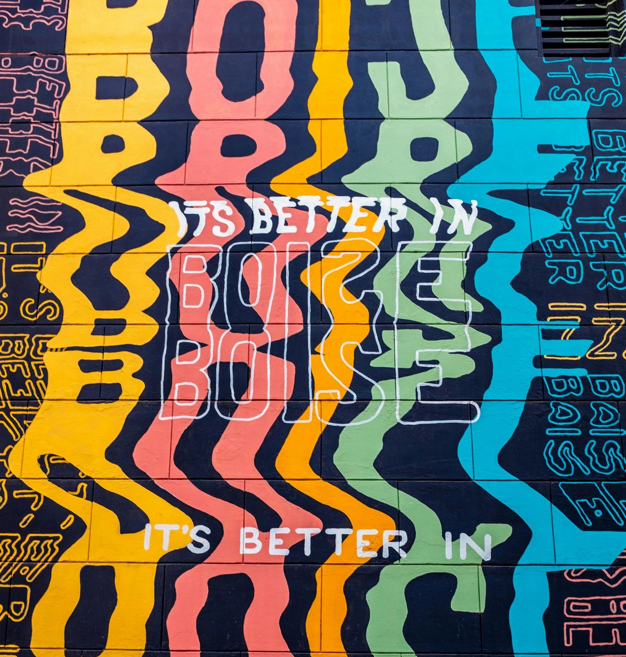 Colorful mural with wavy text: "It's Better in Boise" repeated in various colors and orientations near LOCAL Boise apartments.