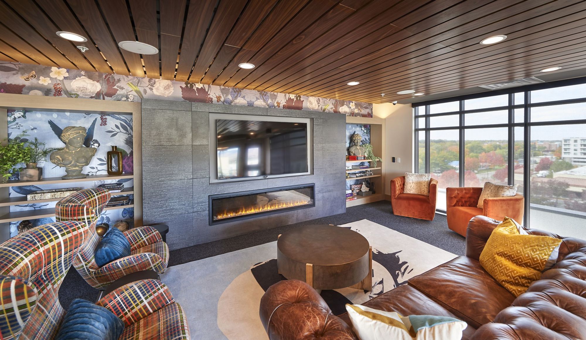 LOCAL Boise Apartments Sky Box lounge with tables, comfortable chairs, and large tv wall with gas fireplace