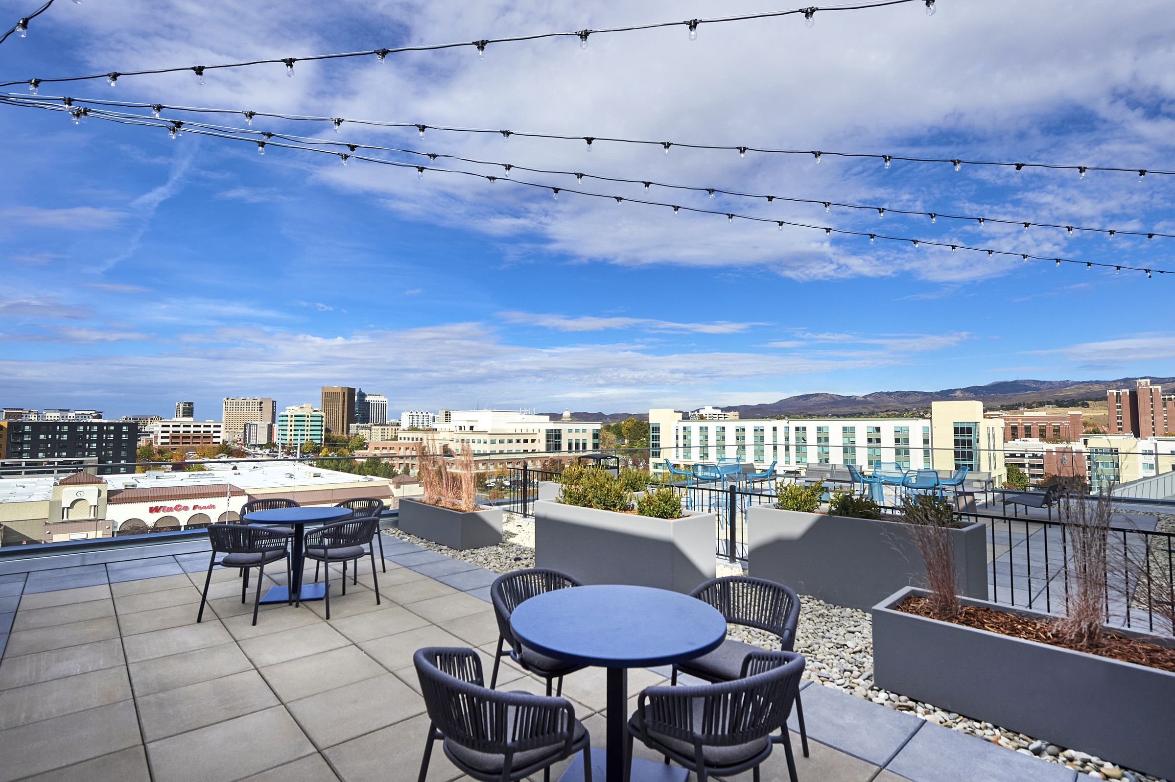 LOCAL Boise Apartments roof deck with tables, chairs, and scenic city views
