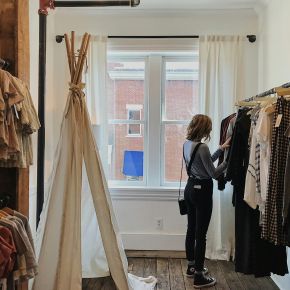 Person browsing clothes in a cozy room with a teepee and a bright window near LOCAL Boise apartments.