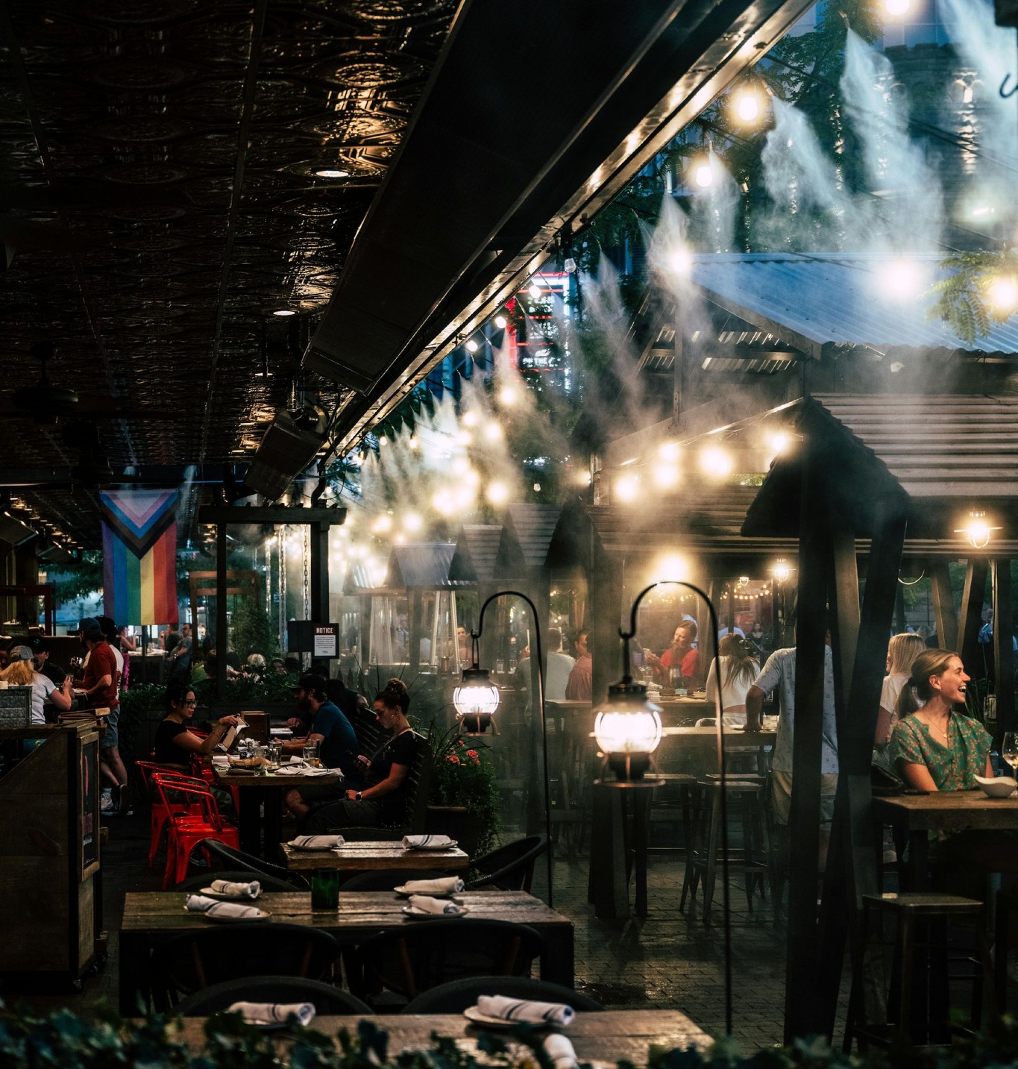 Outdoor restaurant with mist, string lights, and people dining at tables in a dim, cozy atmosphere near LOCAL Boise apartments.