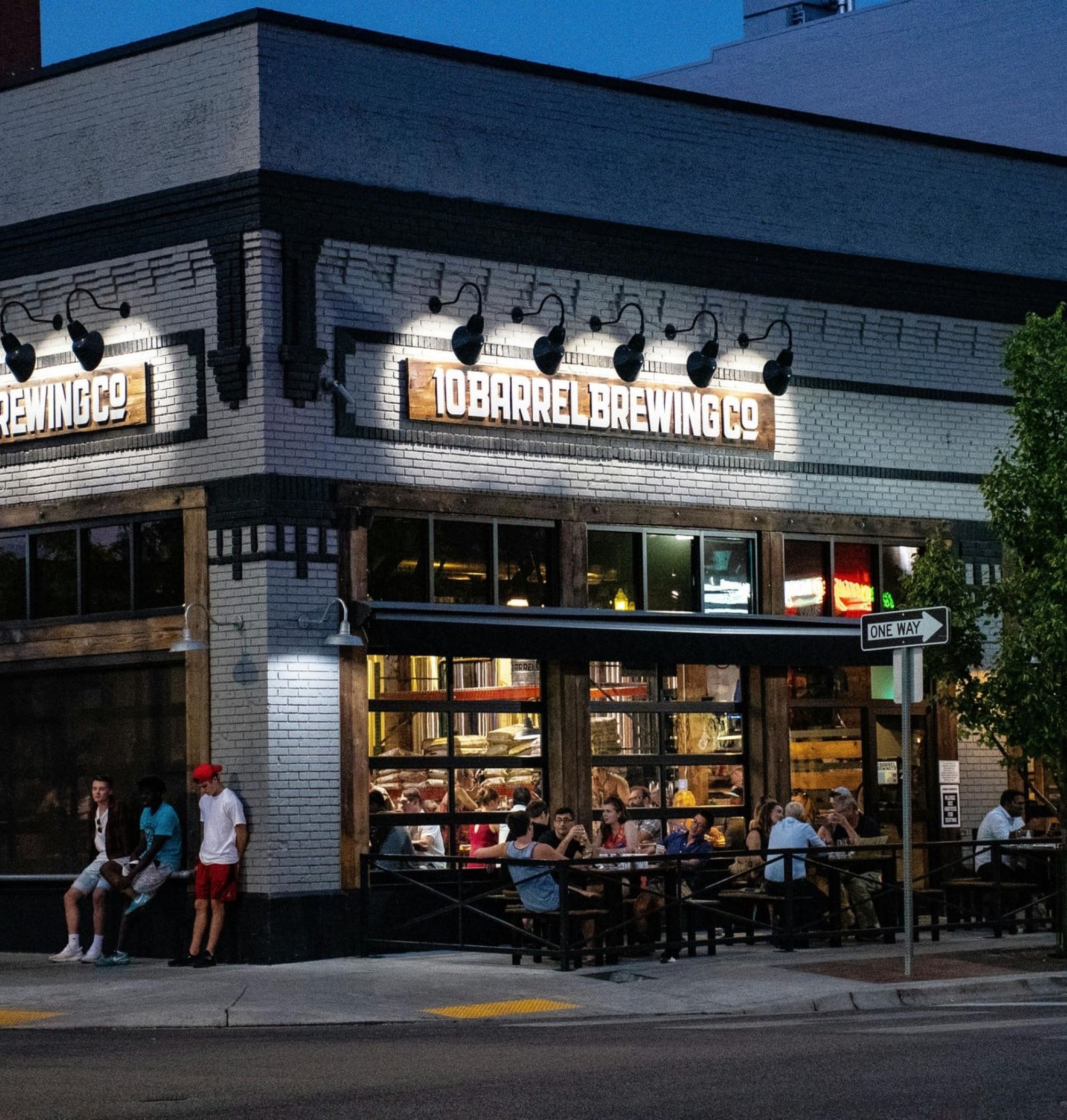 People outside 10 Barrel Brewing Co. restaurant at night, with illuminated sign and street view near LOCAL Boise Apartments.