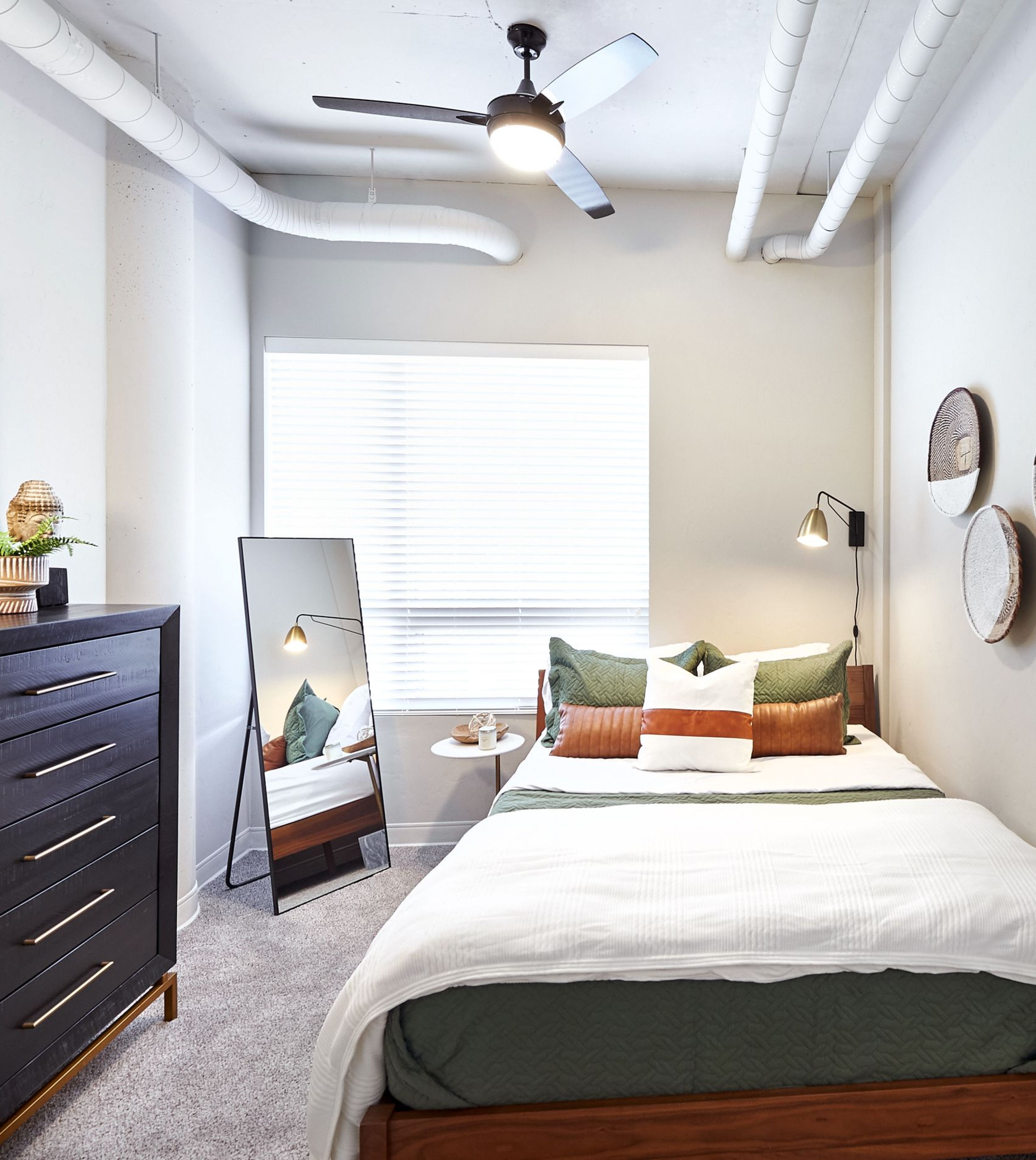 LOCAL Boise Apartments bedroom with plush carpeting, ceiling fan, high ceilings, large window with blinds and modern furnishings