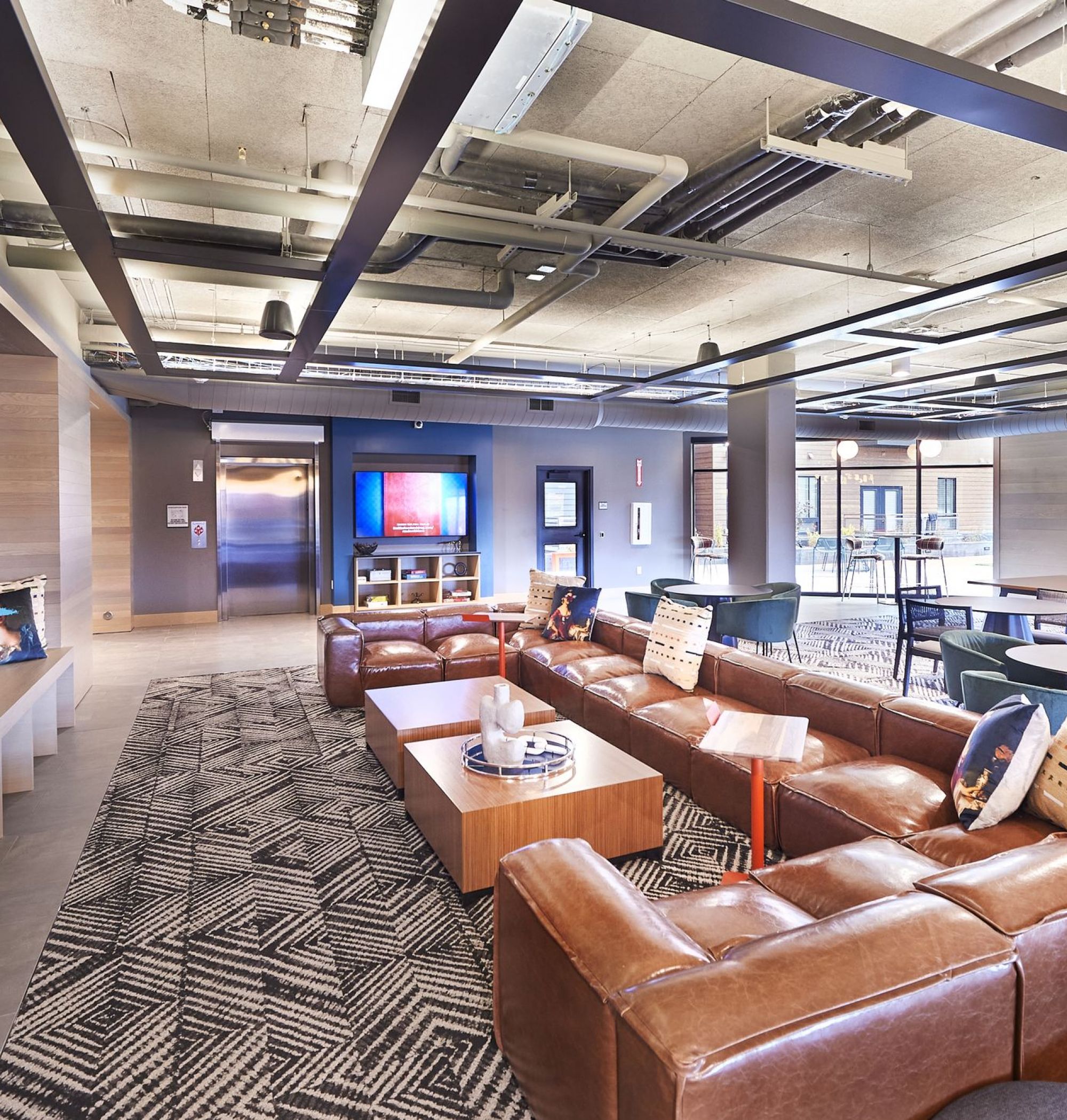 LOCAL Boise Apartments indoor Lounge with comfortable seating, big screen tvs, and tables and chairs