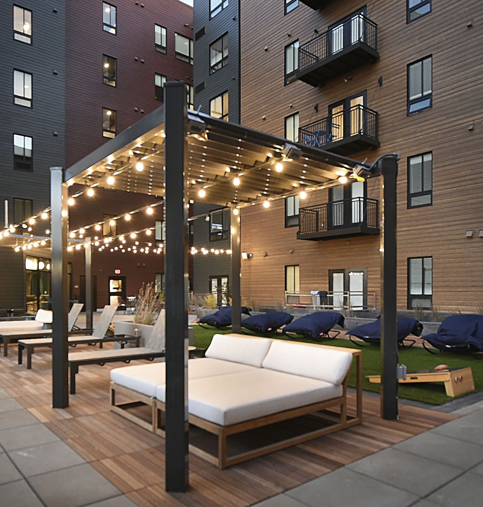LOCAL Boise Apartments outdoor courtyard lounge pergolas with string lights and cornhole court